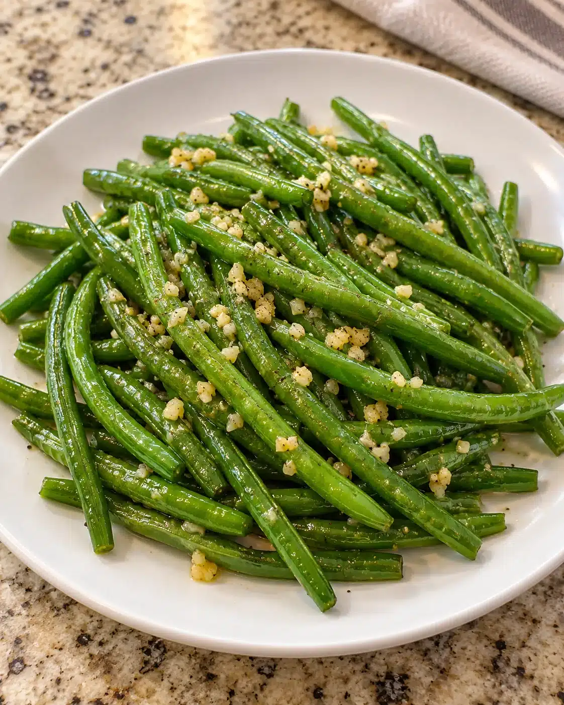 Tender-crisp green beans coated in lemon garlic butter on a white serving plate